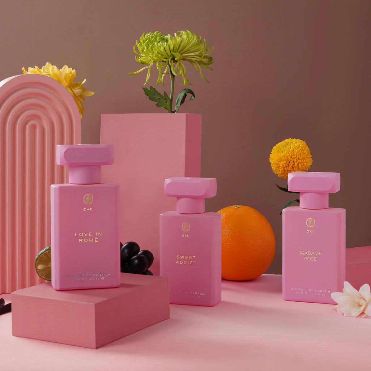 a pink table topped with three bottles of perfume
