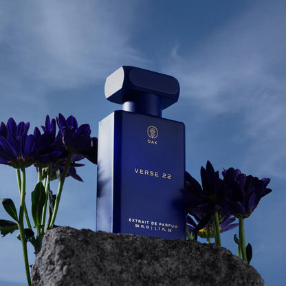 a blue bottle sitting on top of a rock next to purple flowers