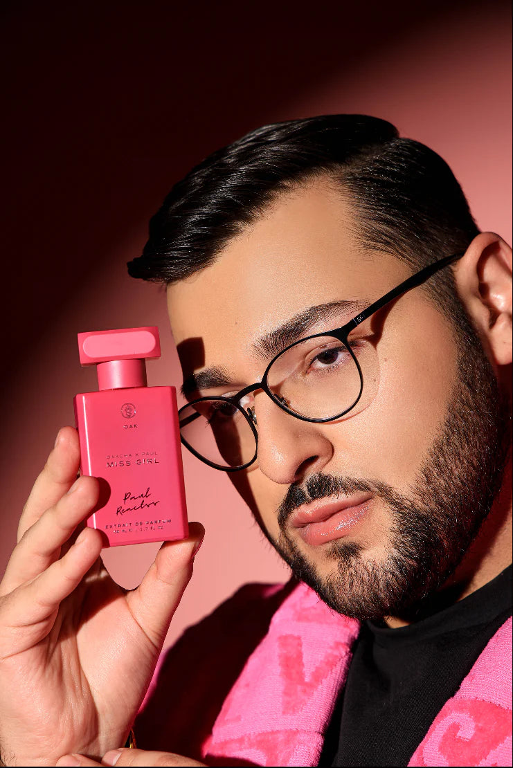 a man with glasses holding a pink perfume bottle