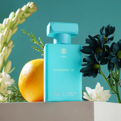 a bottle of perfume next to a flower and an orange